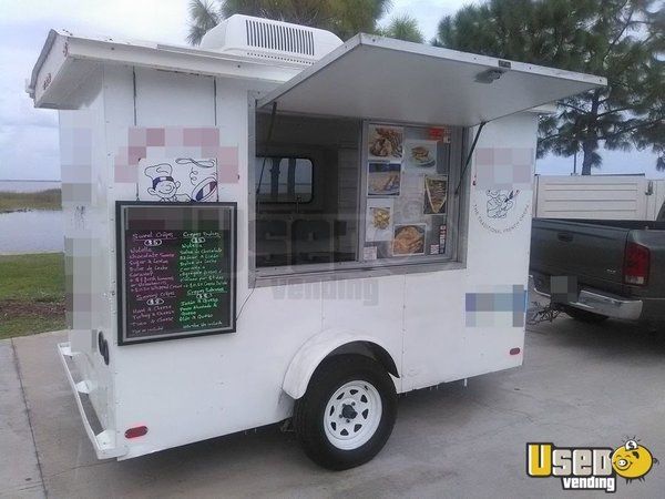 a white food truck parked in front of a lake