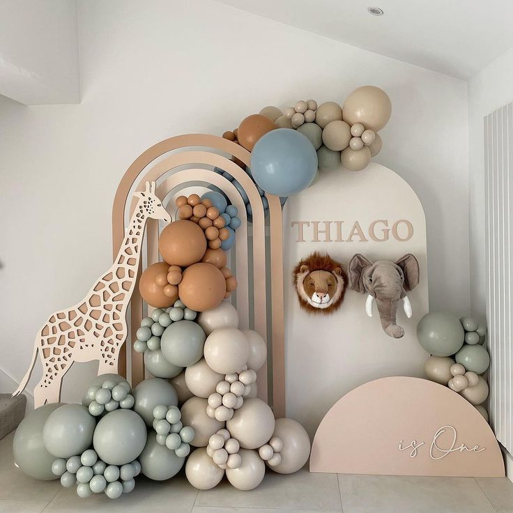 a room decorated with balloons, giraffes and other items in pastel colors