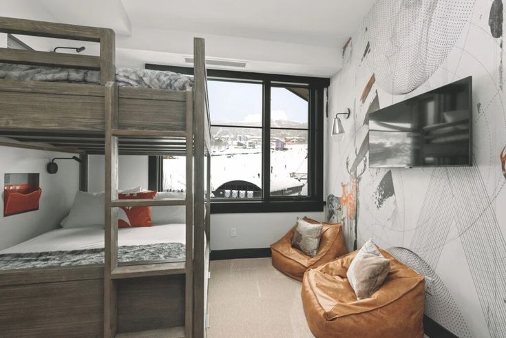 a bedroom with bunk beds and a tv mounted to the wall next to a window