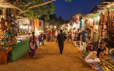 people are walking through an outdoor market at night