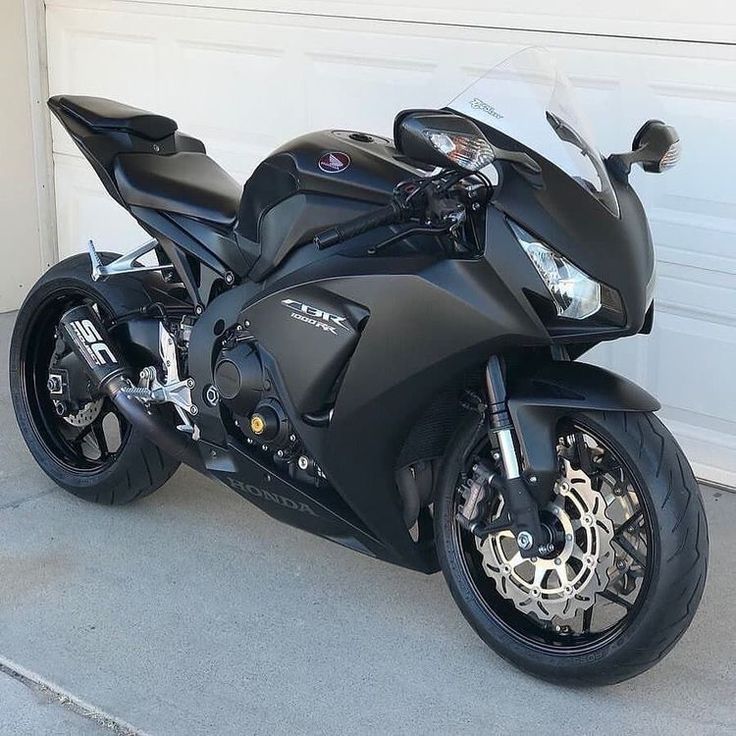 a black motorcycle parked in front of a garage door