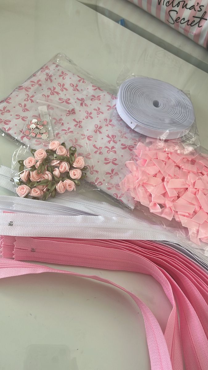 pink flowers and ribbons are sitting on the table next to each other in plastic bags