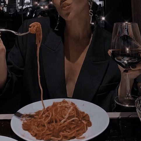 a woman sitting at a table eating spaghetti