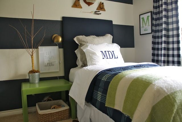 a bed room with a neatly made bed next to a green table and window sill