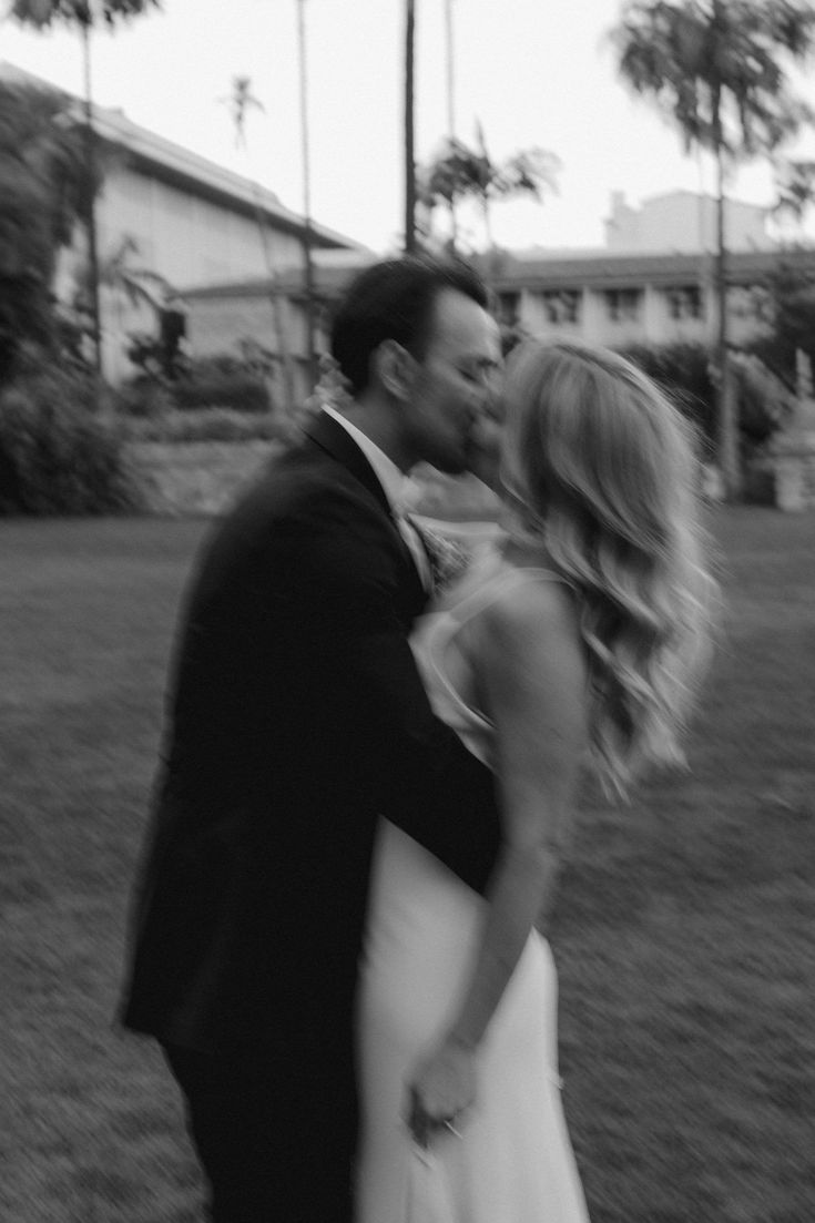 a bride and groom kissing in front of a building with palm trees on the other side