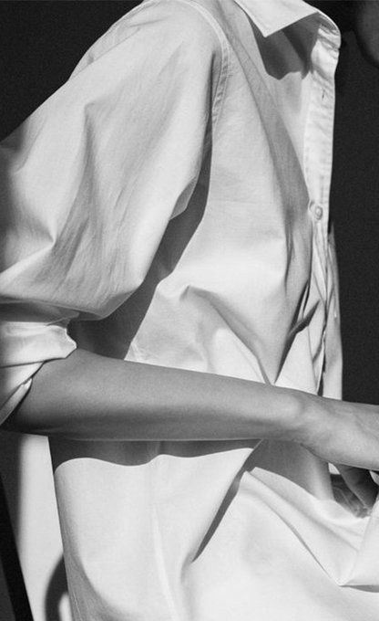 black and white photograph of a woman's hand holding onto a shirt with her left arm