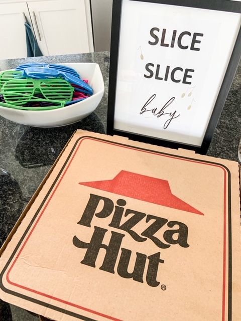 a pizza hut sign sitting on top of a counter next to a bowl of fruit