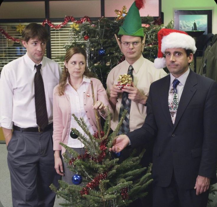 three people standing next to each other in front of a christmas tree