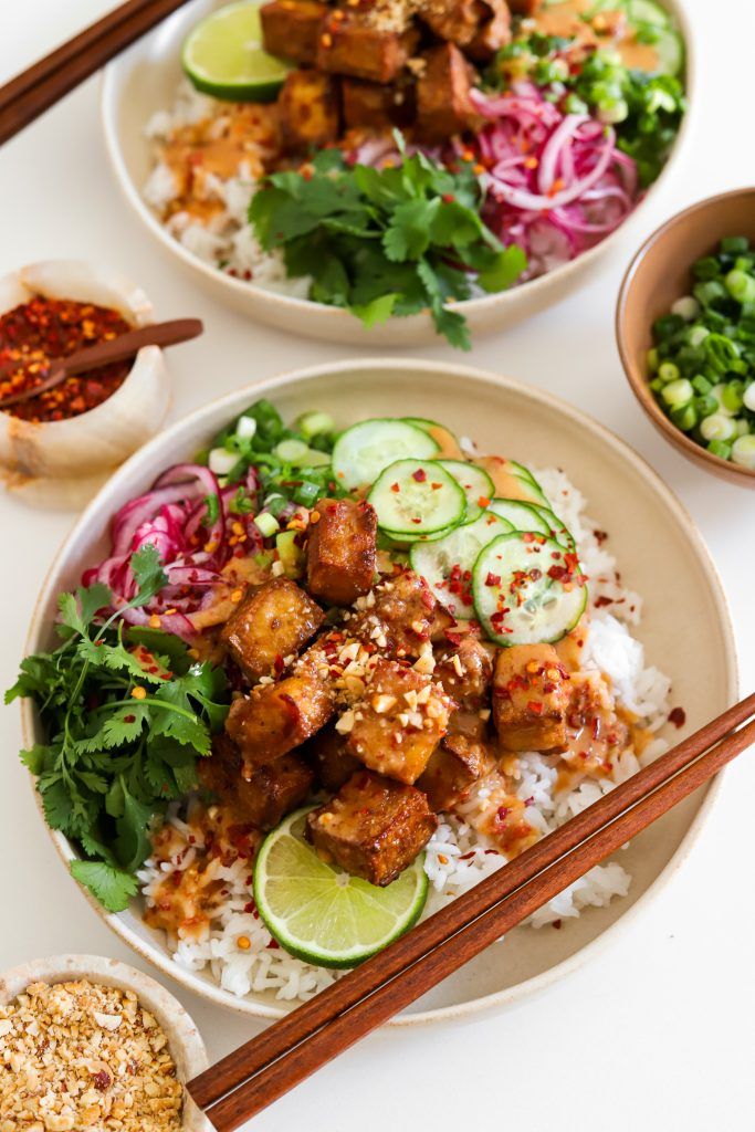 two plates filled with rice, meat and veggies next to chopsticks