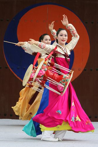 two women in colorful dresses are dancing on stage