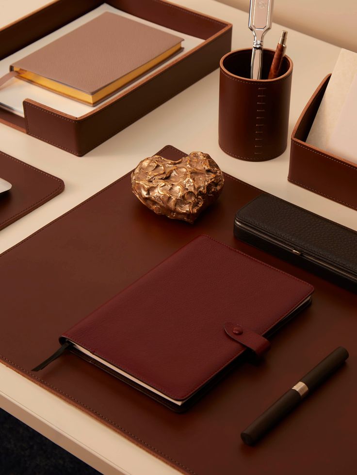 a desk with various items on it including a pen, notebook and cell phone sitting next to each other