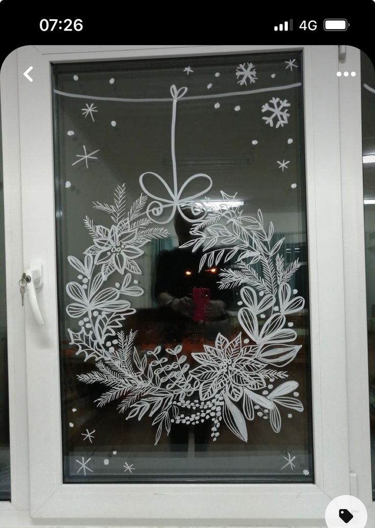 a frosted glass window decorated with white snowflakes and wreaths on it