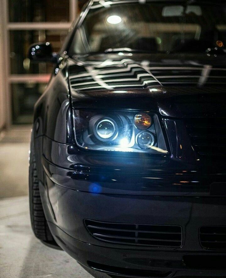 the front end of a black car with its lights on