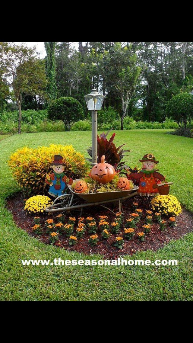 a wheelbarrow filled with pumpkins and gourds in the middle of a garden