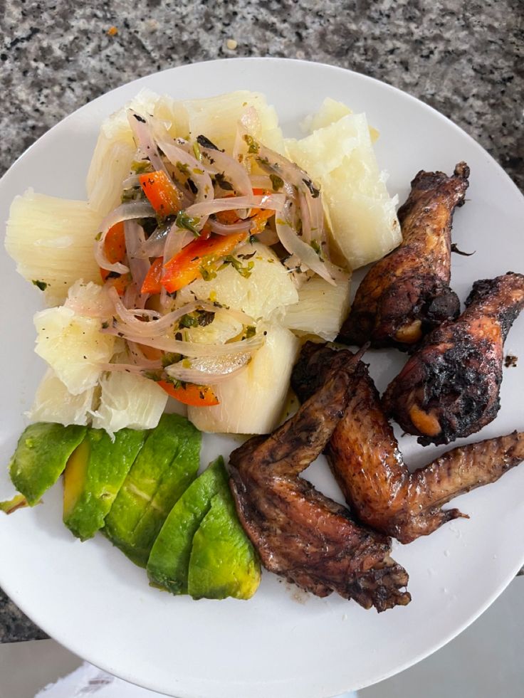 a white plate topped with meat and veggies on top of a marble table