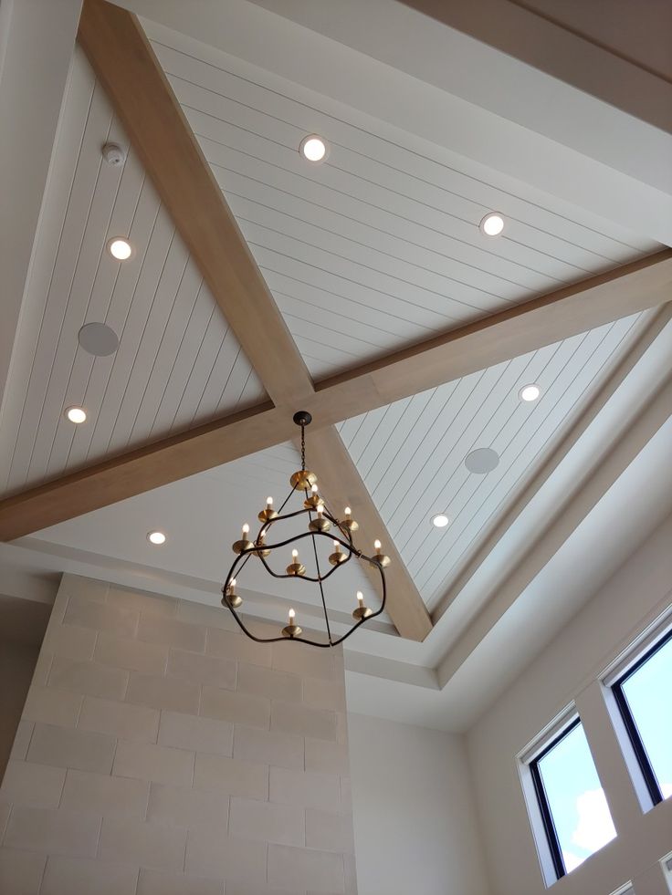 a chandelier hanging from the ceiling in a room with white walls and beams