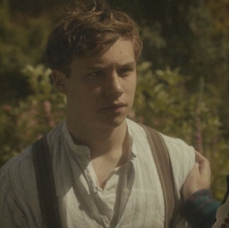 a man and woman standing next to each other in front of some bushes with flowers