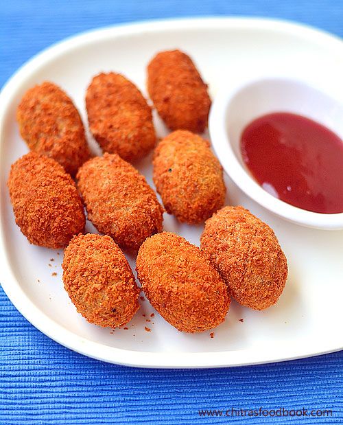 some fried food on a white plate next to a small bowl of ketchup