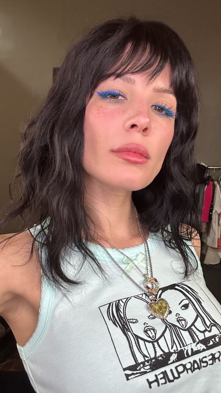 a woman with dark hair and blue eyes wearing a tank top