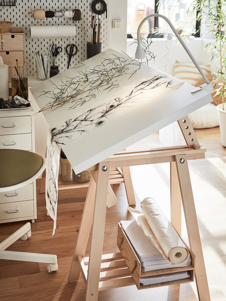 an artist's easel sitting on top of a hard wood floor next to a desk