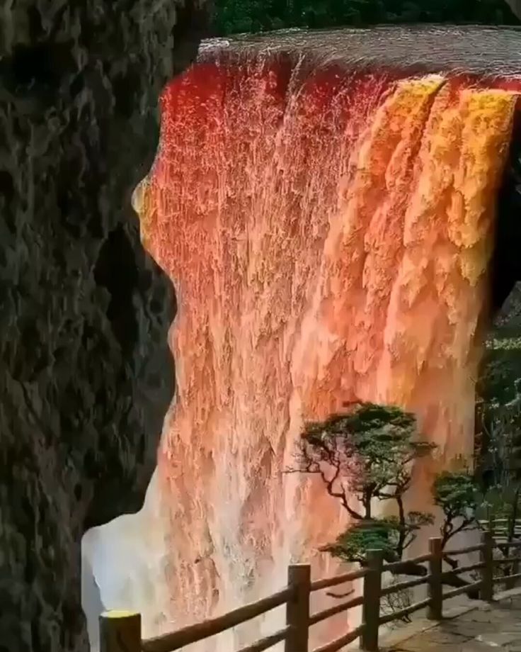 a large waterfall with red and orange water