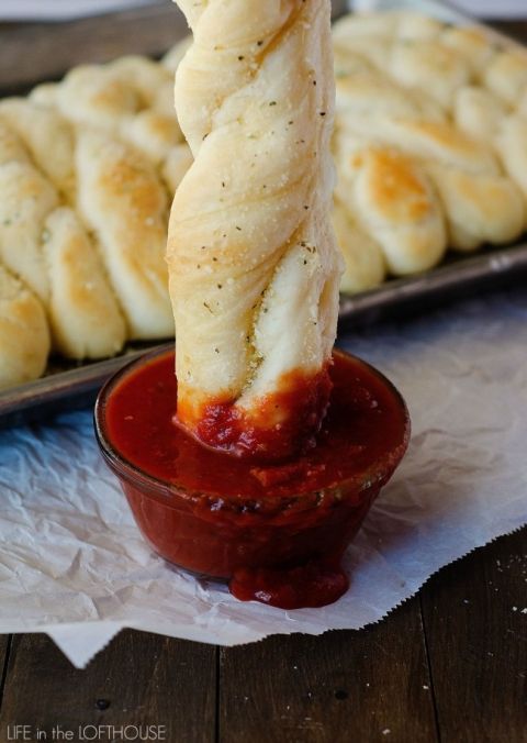 bread sticks sticking out of a small bowl of marinara sauce