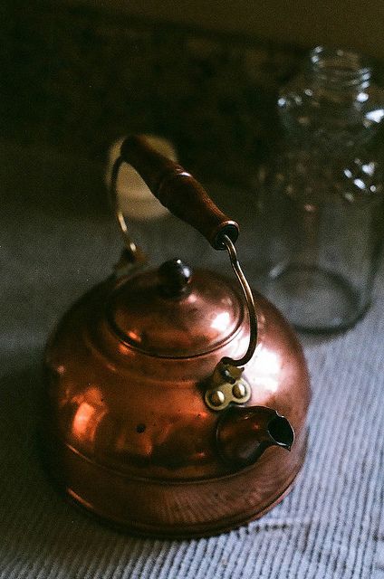 a copper tea kettle sitting on top of a table