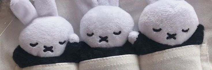 three white stuffed animals sitting on top of each other in front of a person's shirt