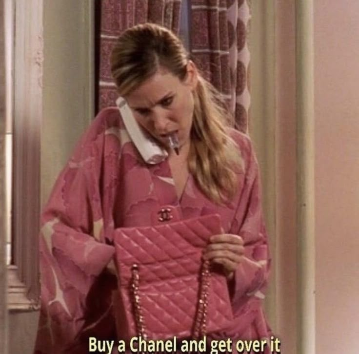 a woman wearing a pink jacket and holding a purse in her hand with the caption, buy a chanel and get over it