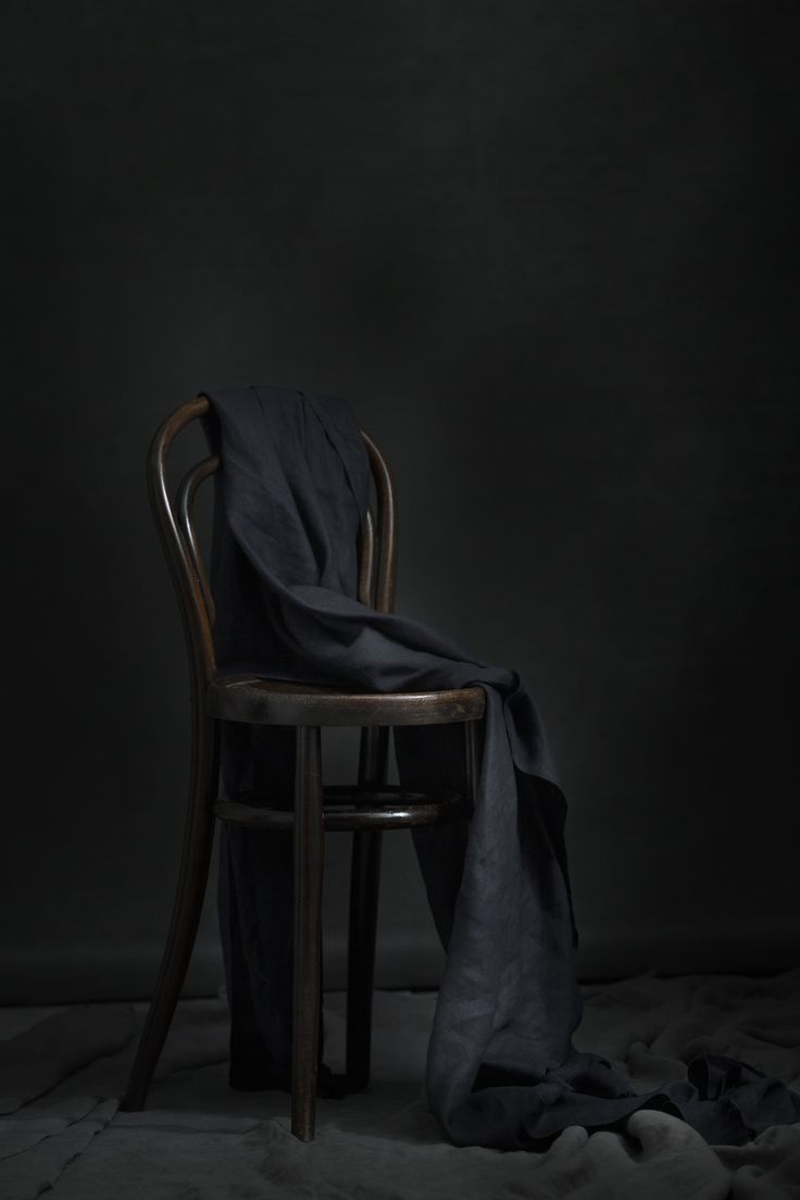 a chair with a blanket on top of it in front of a dark wall and floor