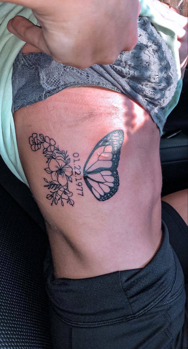 a woman's stomach with a butterfly and flowers tattoo on her side ribcage