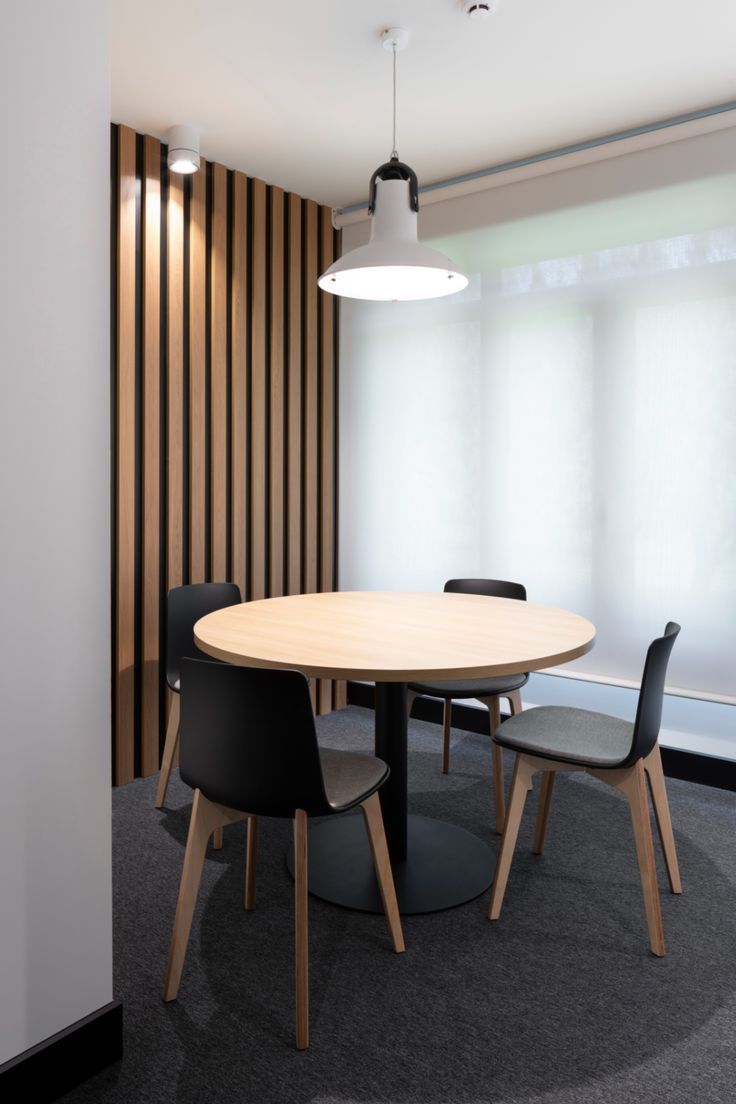 a round table with chairs around it in an office setting that has vertical blinds on the windows