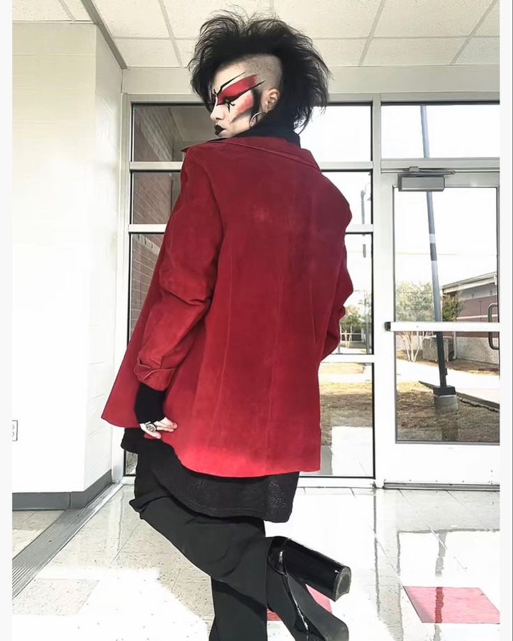 a man in a red jacket and black pants with his hair styled to look like an alien