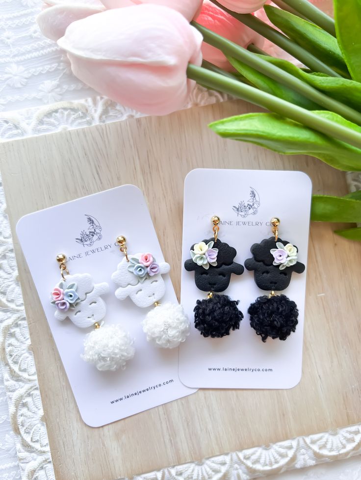 two pairs of black and white pom - pom earrings sitting on top of a table