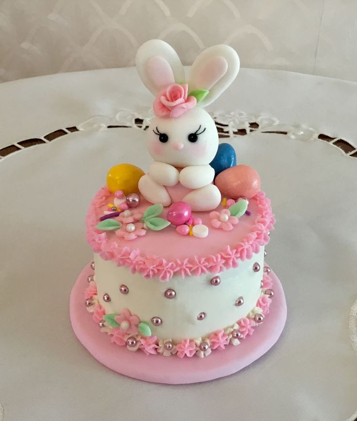 a small cake decorated with an easter bunny sitting on it's side and eggs in the middle