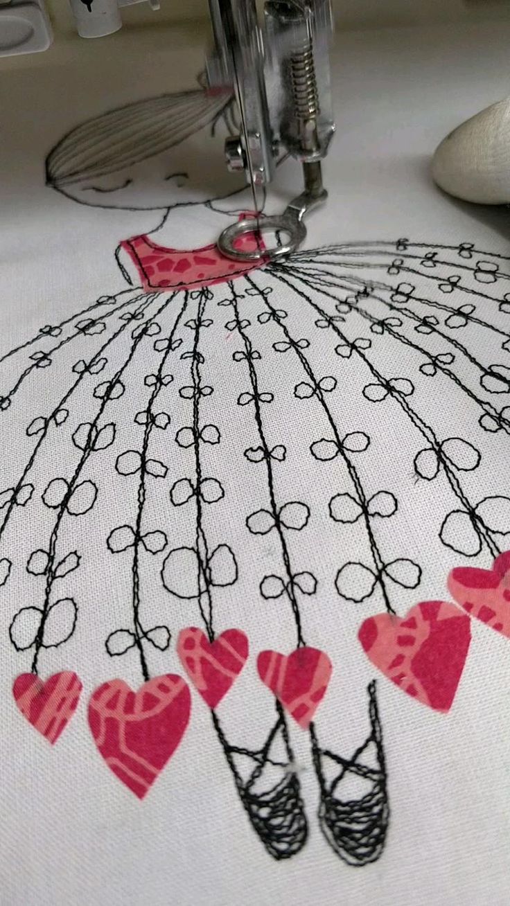 an embroidered umbrella with hearts on it sitting on a table next to a sewing machine