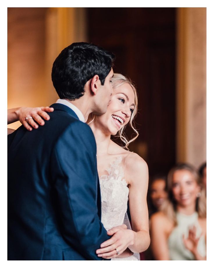 a bride and groom sharing a hug at their wedding ceremony in front of an audience