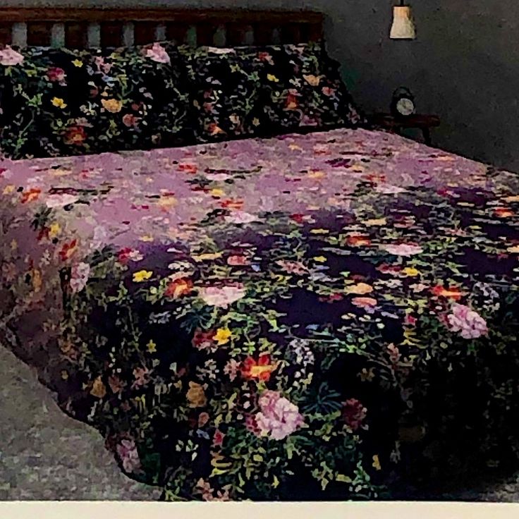 a bed with a purple flowered bedspread and matching comforter is shown