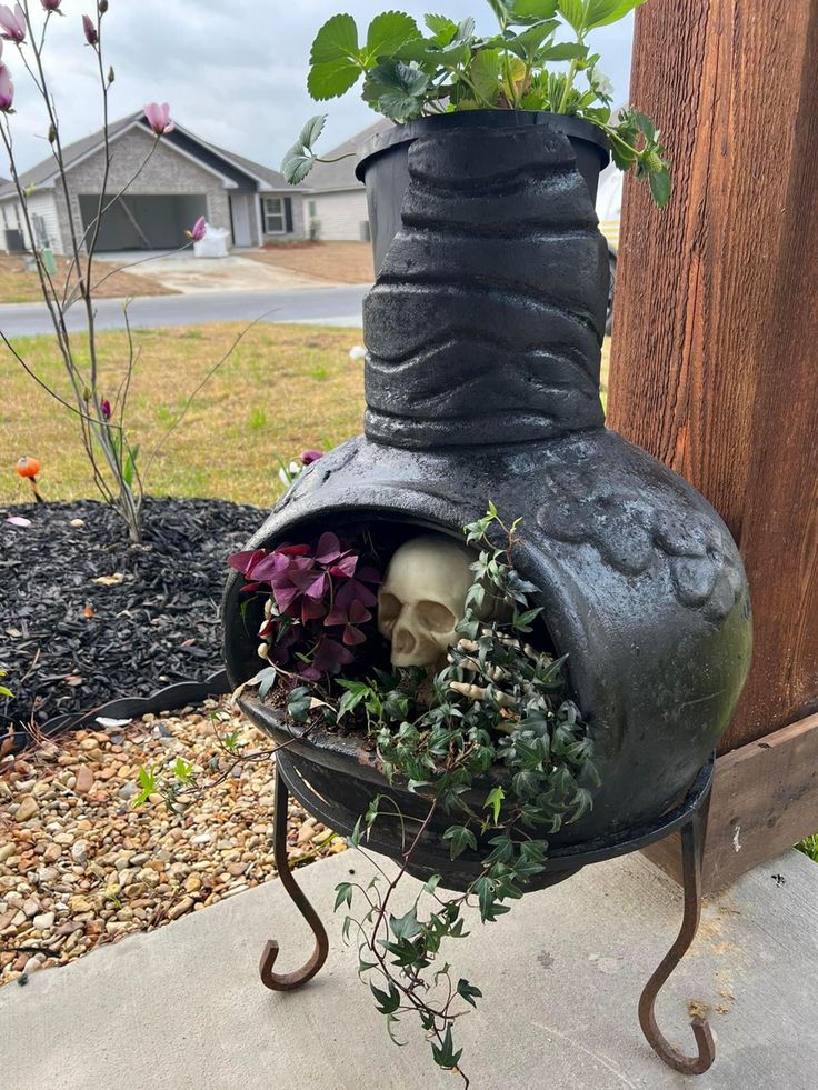 a potted plant with a skull head in it sitting on a stand next to a fence