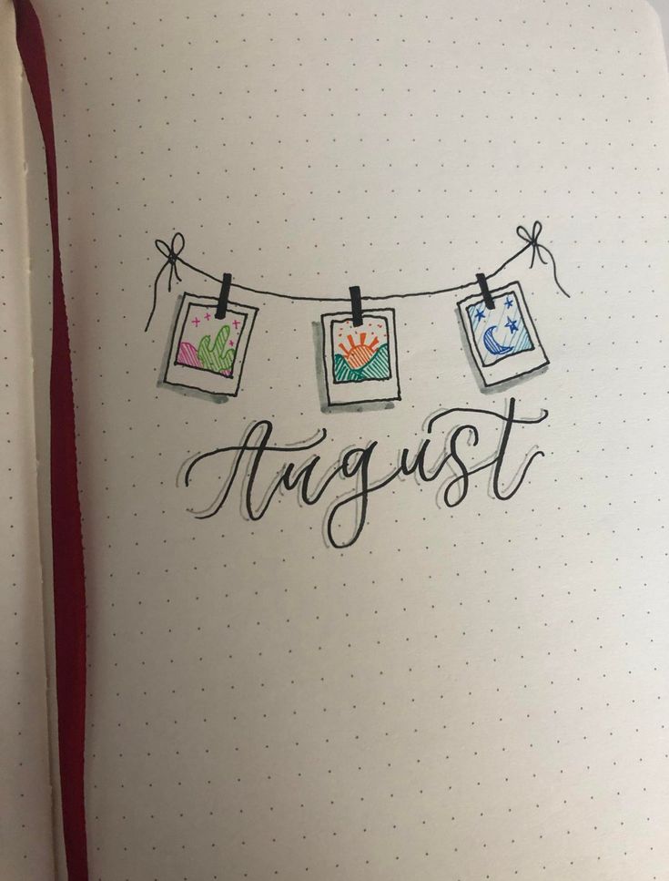 an open notebook with the word august hanging on a line and pictures pinned to it