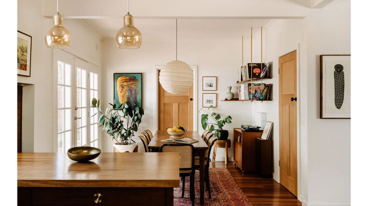 a dining room and living room area with wood floors, white walls and wooden furniture