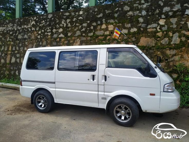 a white van parked in front of a stone wall