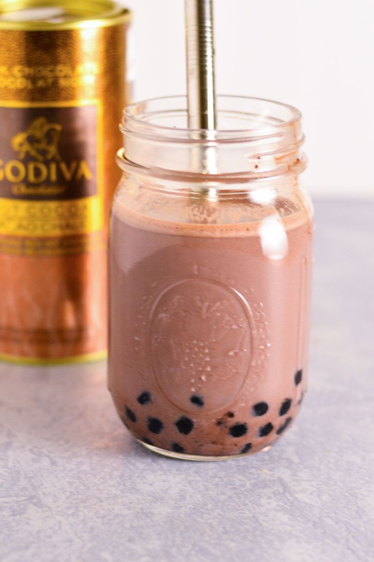 a glass jar filled with chocolate drink next to a gold tin can and an empty bottle