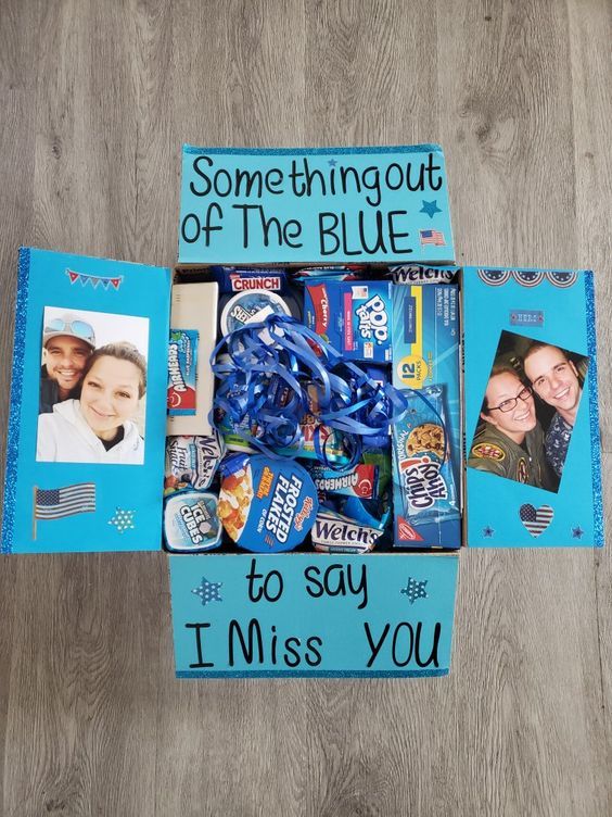 a blue box filled with candy and candies on top of a wooden floor next to two pictures