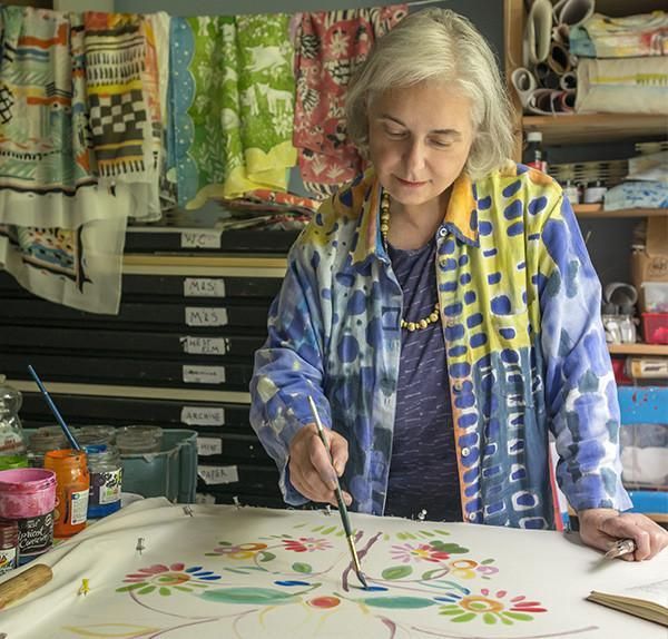 an older woman is working on some art work