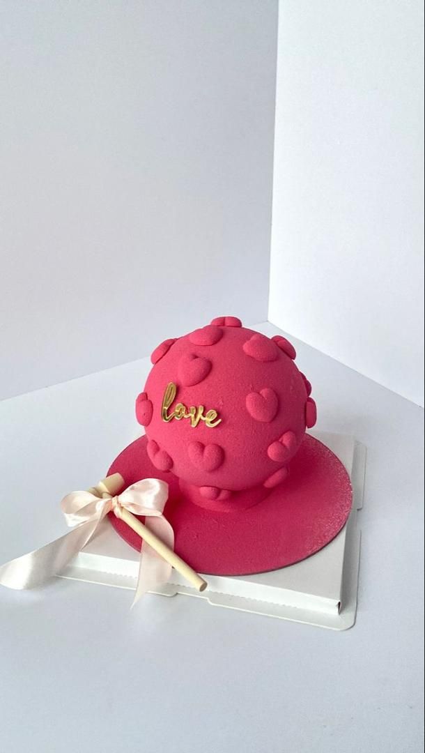 a pink cake with gold lettering on it