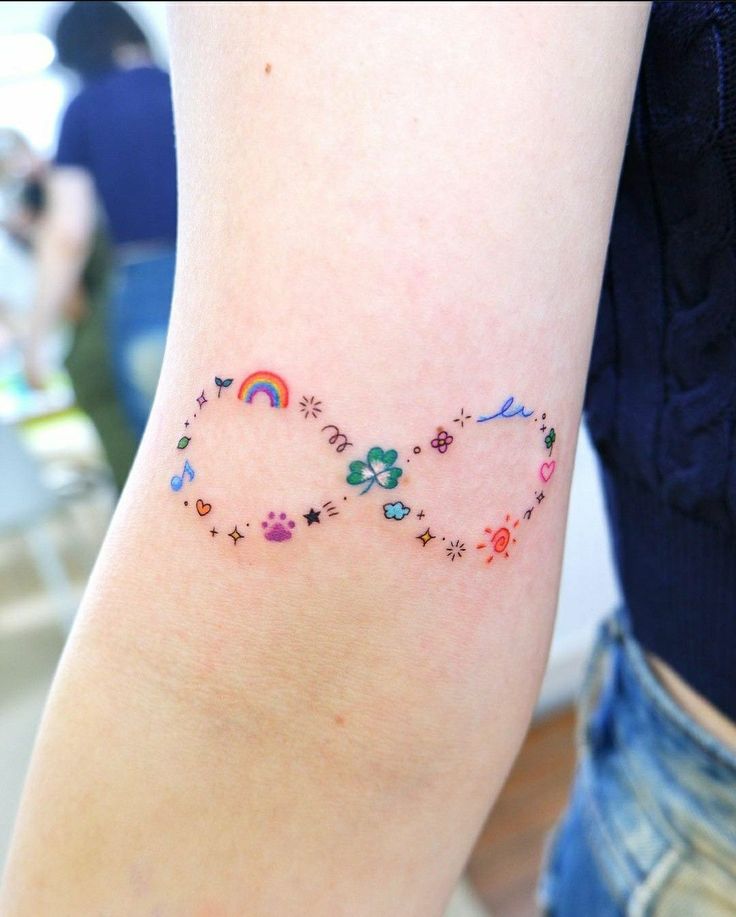 a person with a tattoo on their arm that has different colored stars and rainbows