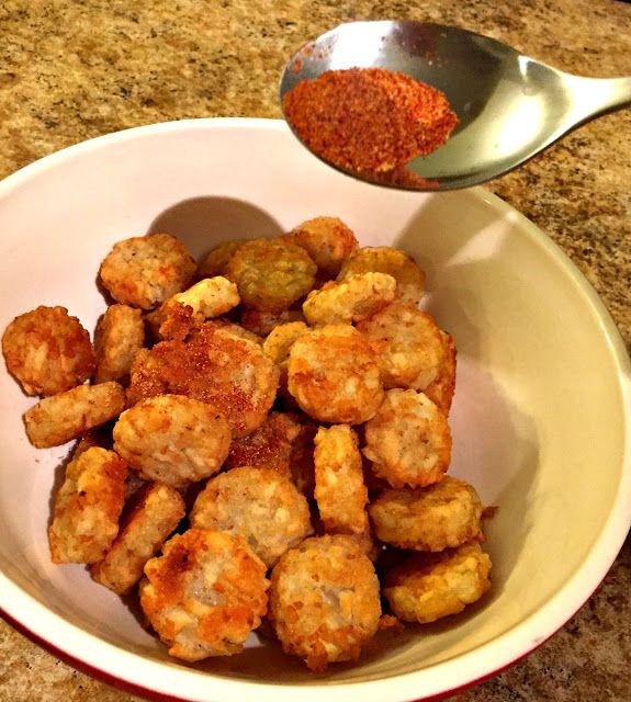 a white bowl filled with fried food next to a spoon on top of a counter