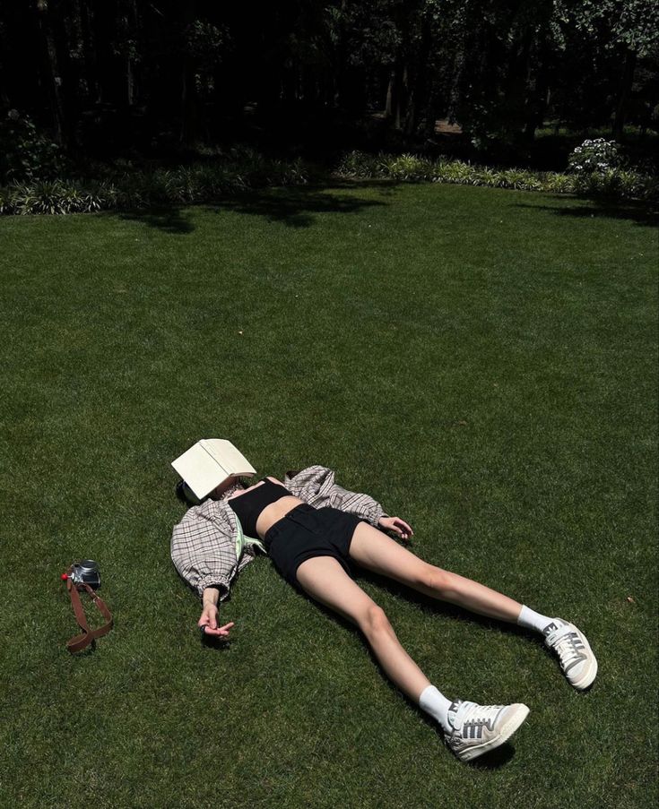 a woman laying on the grass reading a book