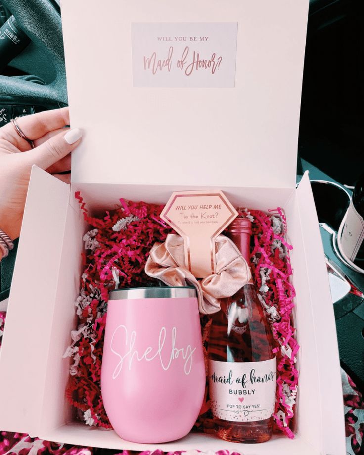 a pink wine bottle in a gift box with a bow on the top and a personalized tumbler next to it